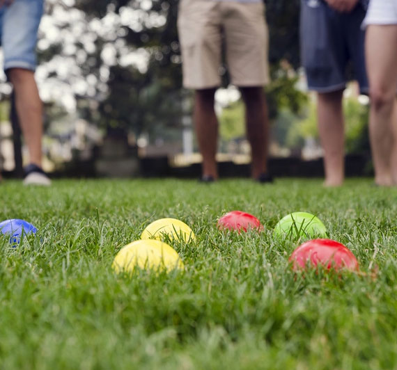 Outdoor farm activity where colourful balls are placed on a field with people standing around them ready for the fun