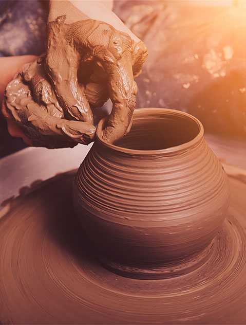 Closeup view of clay smeared hands skillfully crafting a mud pot